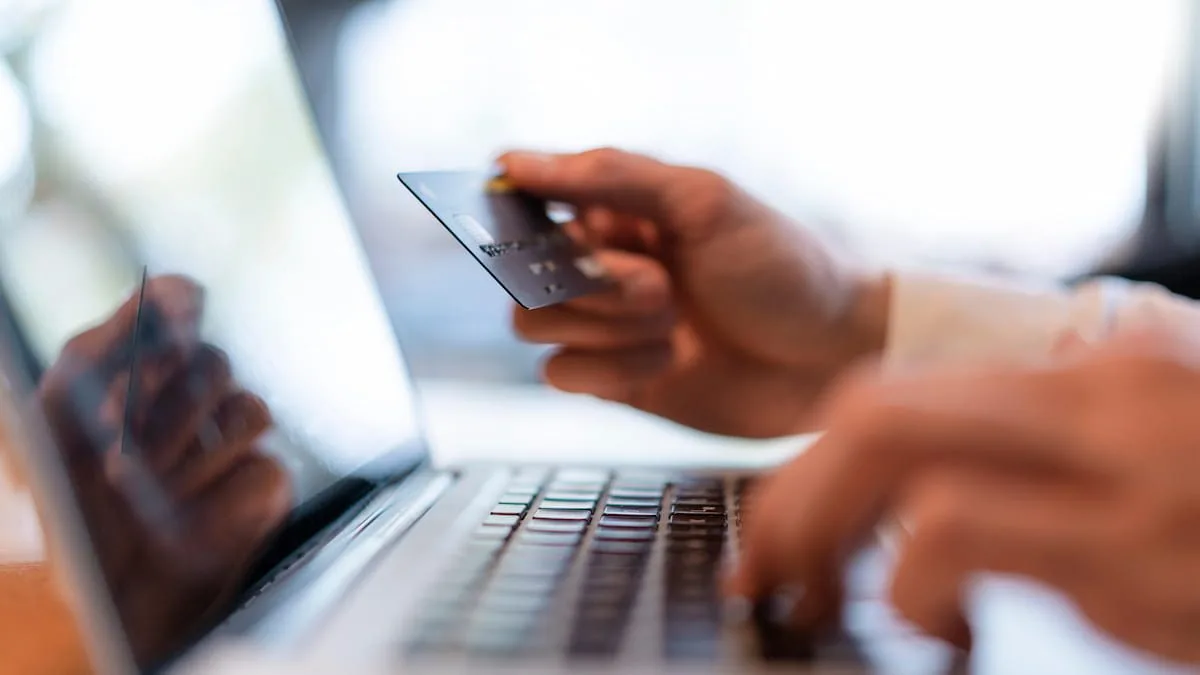 A man is holding his ID card close to the laptop as he types in its details.